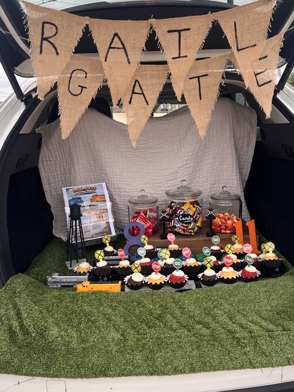 A car trunk decorated with train-themed cupcakes in a variety of colors