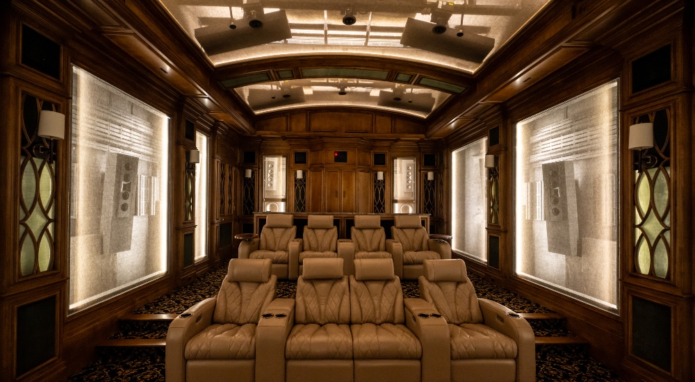 Wide view of luxury private cinema seating in a subterranean home theater in Dallas Texas, with transparent acoustic baffles revealing in-ceiling JBL Synthesis speaker installations as part of a 28-driver Dolby Atmos system designed and integrated by Elliston Systems & Design