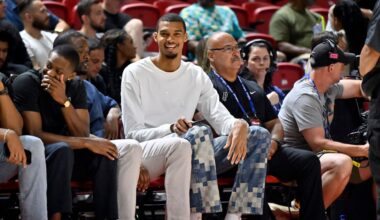 San Antonio Spurs' Victor Wembanyama, center, sits court side during the first half of an NBA summer league basketball game between the Spurs and Philadelphia 76ers, July 10, 2025, in Las Vegas. (AP Photo/David Becker, File)