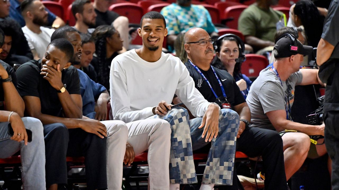 San Antonio Spurs' Victor Wembanyama, center, sits court side during the first half of an NBA summer league basketball game between the Spurs and Philadelphia 76ers, July 10, 2025, in Las Vegas. (AP Photo/David Becker, File)