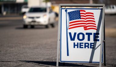 a sign for a voting location with an American flag.
