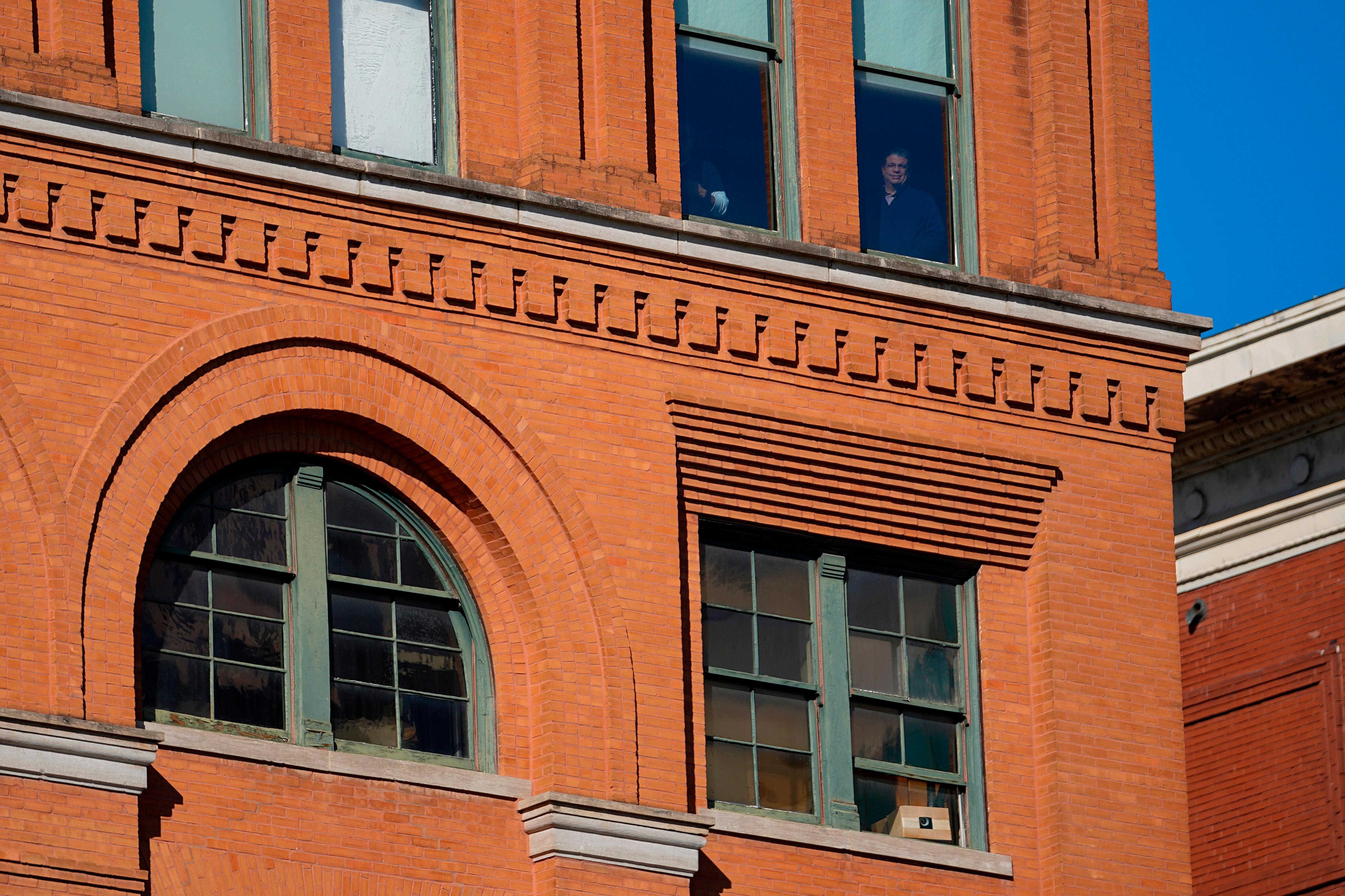 People stand at windows one floor above the 6th floor of the book depository at Dealey Plaza