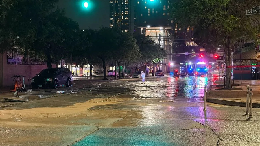 Water main break causes flooding at intersection of 6th and Red River Streets early the morning of Monday, April 13, 2026. (KXAN Photo/Todd Bailey)