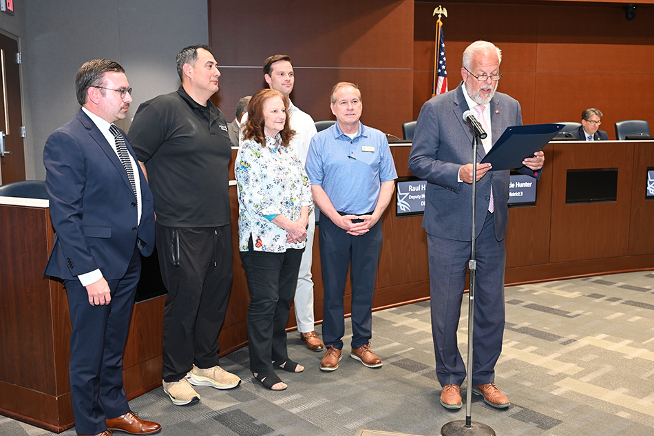 Mayor Jim Ross reads proclamation while five people stand behind him.