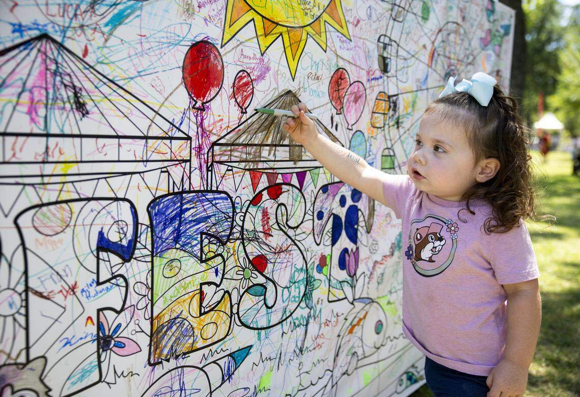 Nora Gibson, 2, colors on a community mural near the children's area of Mayfest on Saturday, May 2, 2026, in Fort Worth.