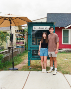 image of two students standing in front of a shed where they sell bread