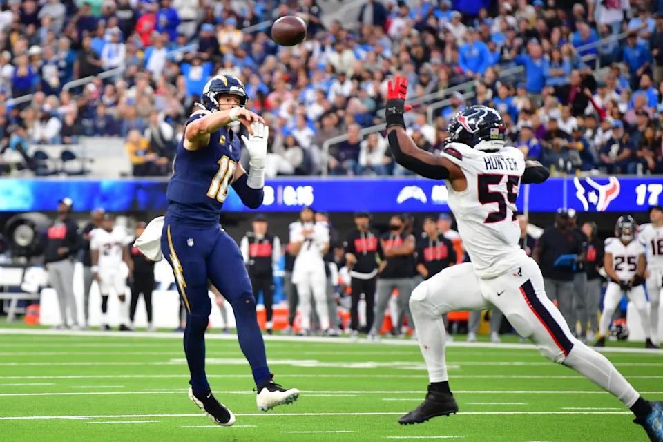 Los Angeles Chargers quarterback Justin Herbert (10) throws a touchdown pass as Houston Texans defensive end Danielle Hunter (55) defends during the second half at SoFi Stadium. Gary A. Vasquez-Imagn Images