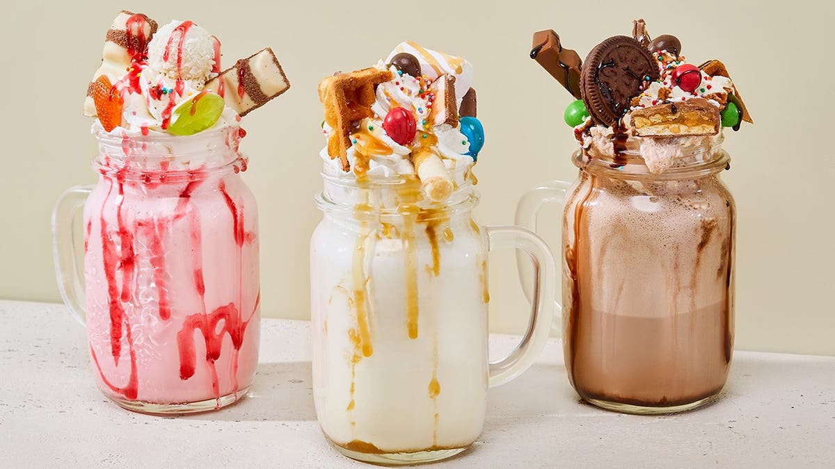 Colorful monster milkshakes with vibrant toppings arranged creatively.