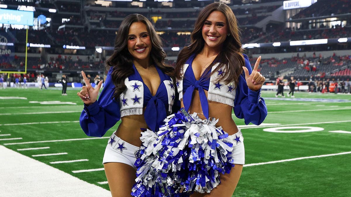 Two Dallas Cowboys cheerleaders standing on the field at AT&T Stadium