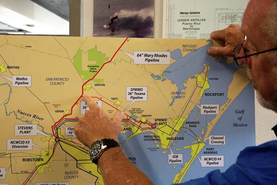 John Michael points to Sinton on a map at the Hanson Professional Services office in Corpus Christi. (Dylan Baddour/Inside Climate News)