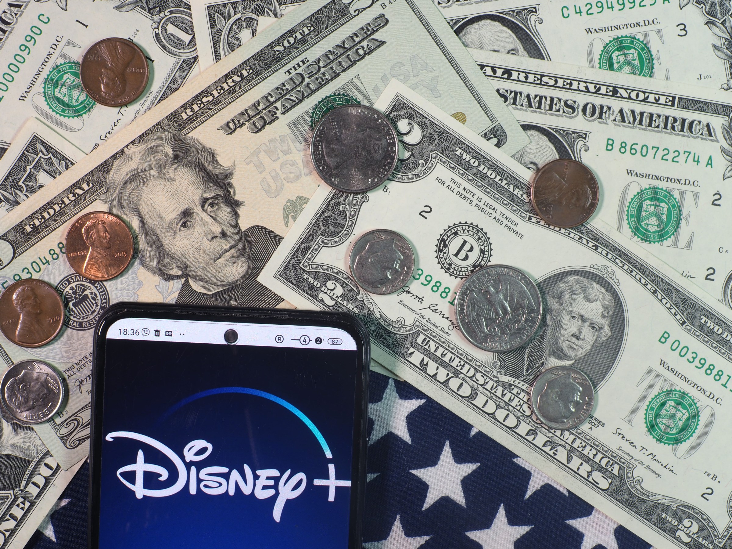 GERMANY - 2023/09/28: In this photo illustration, Disney+ logo seen displayed on a smartphone with United States Dollar notes and coins in the background. (Photo Illustration by Igor Golovniov/SOPA Images/LightRocket via Getty Images)