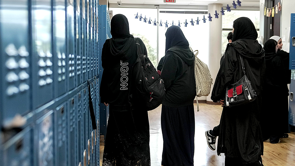 Female students in hijabs at school lockers