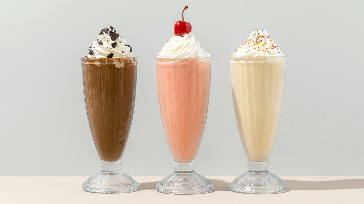 Mixed flavor milkshakes lined up on a counter at a cafe