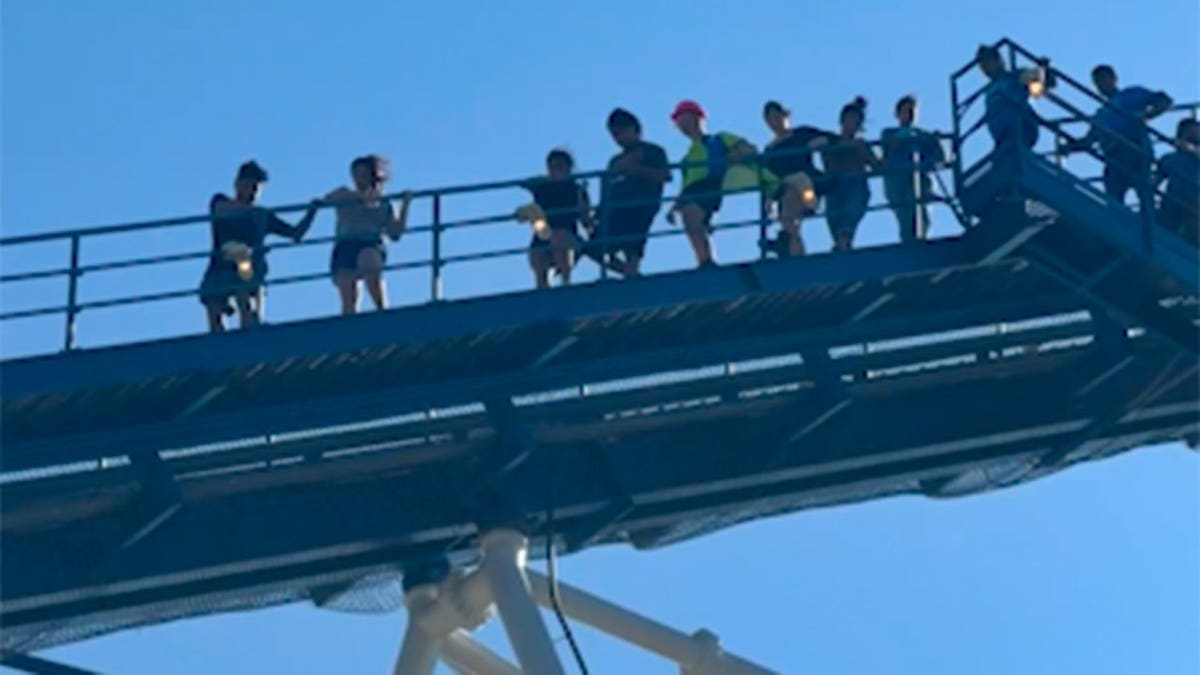 People evacuate from the top platform of a large blue roller coaster at Six Flags in Texas.