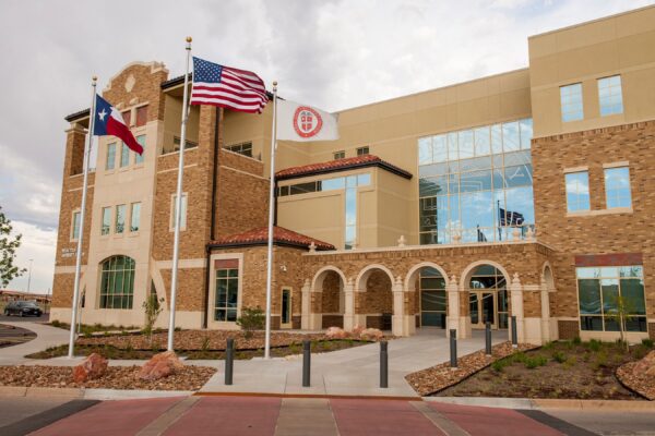 A three-story university adminstration building under a cloudy sky.