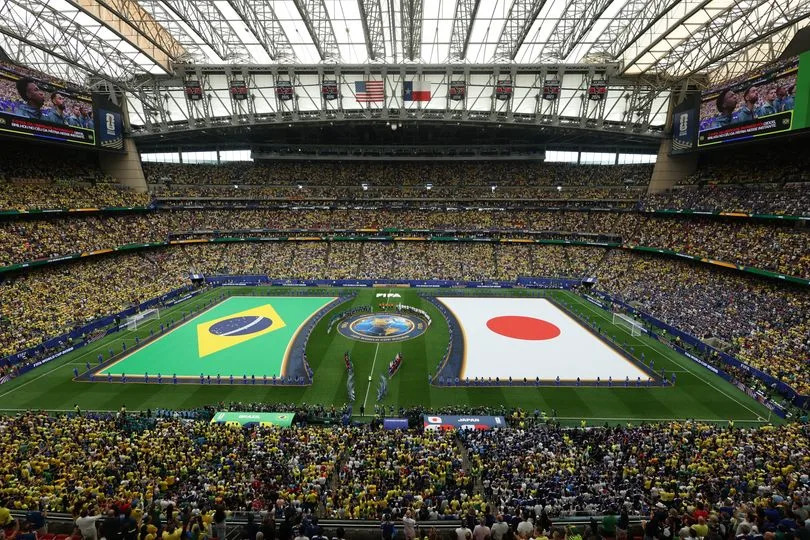 HOUSTON, TEXAS - JUNE 29: Players and officials line up as two large flags are displayed on the pitch during the national anthems prior to the FIFA World Cup 2026 Round Of 32 match between Brazil and Japan at Houston Stadium on June 29, 2026 in Houston, Texas. (Photo by Omar Vega/Getty Images)