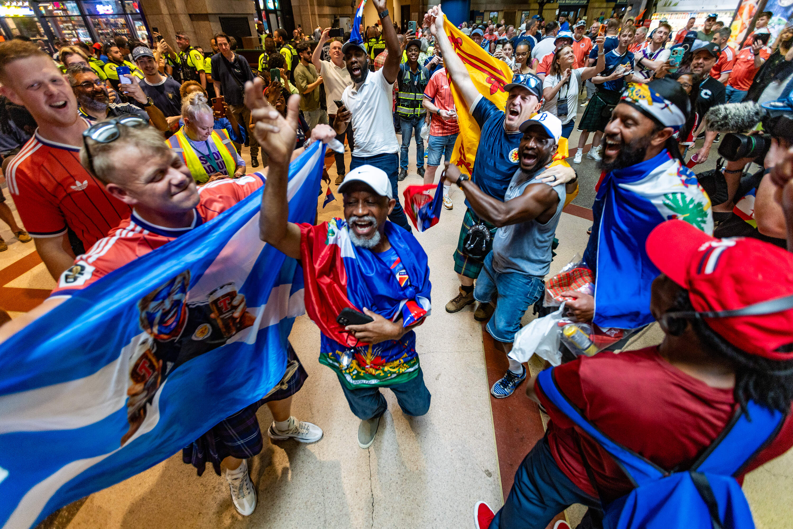 Scottish and Haitian fans dance and chant together inside South Station waiting to board MBTA trains to the World Cup match between Scotland and Haiti to Foxborough. (Jesse Costa/WBUR)