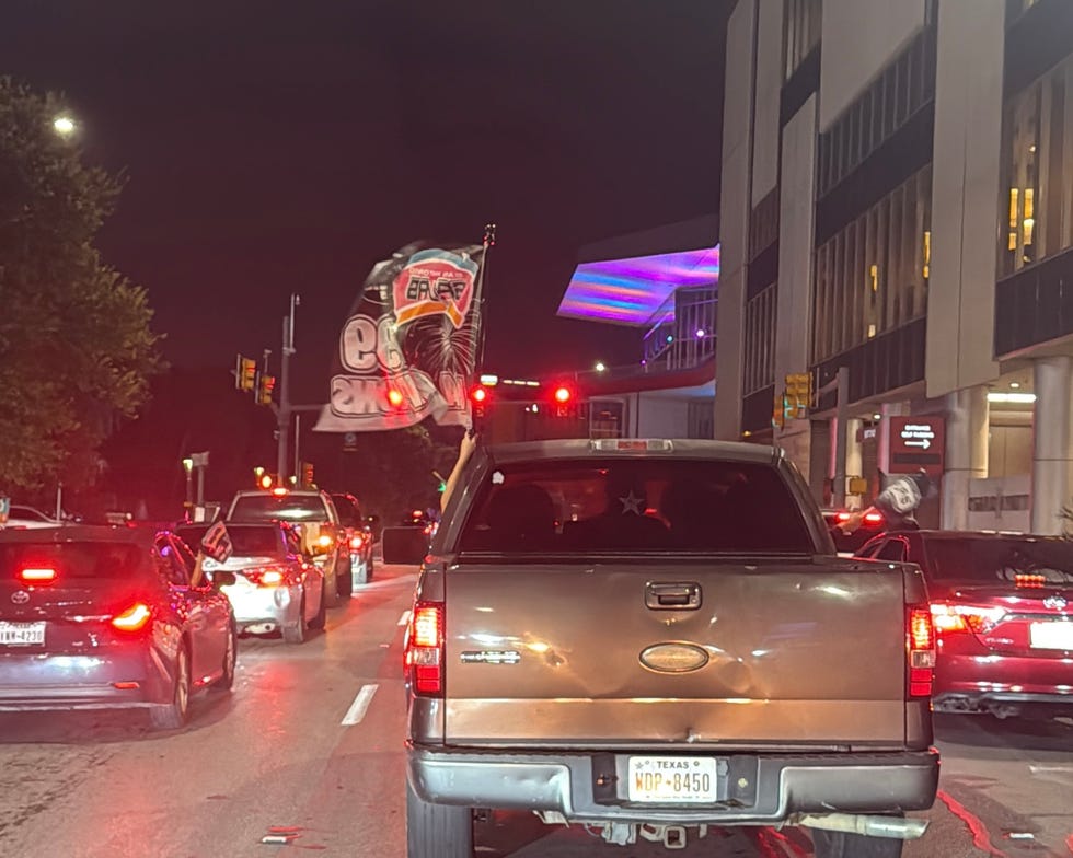 traffic scene at night with vehicles and flags