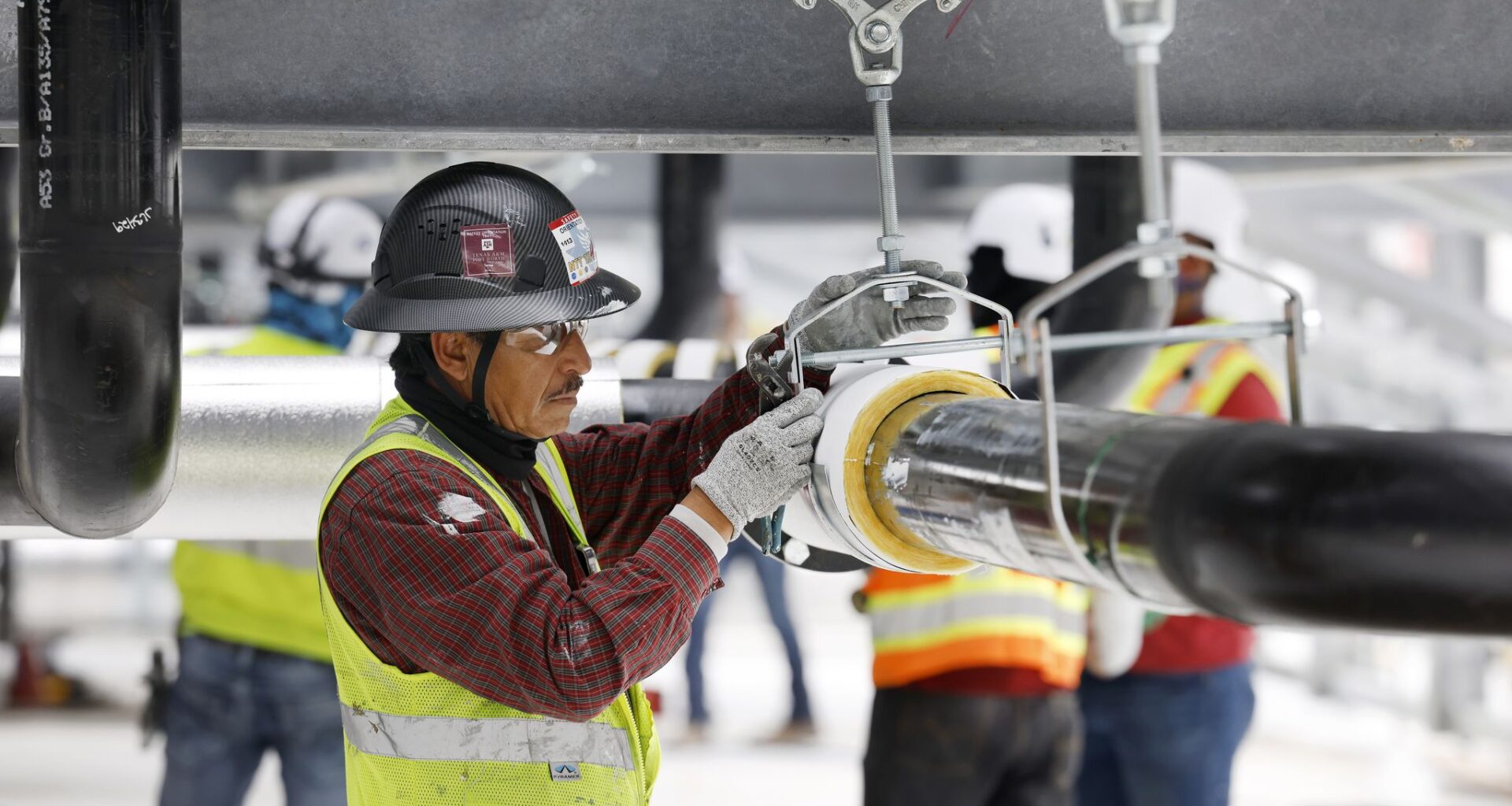 Construction workers build out the rooftop chillers and water lines feeding them atop Dallas TX4, which is under construction at the NTT Data center campus in Garland, Texas, March 4, 2026. It will take 40 of those water-filled chillers to cool the fourth data center built on the property.