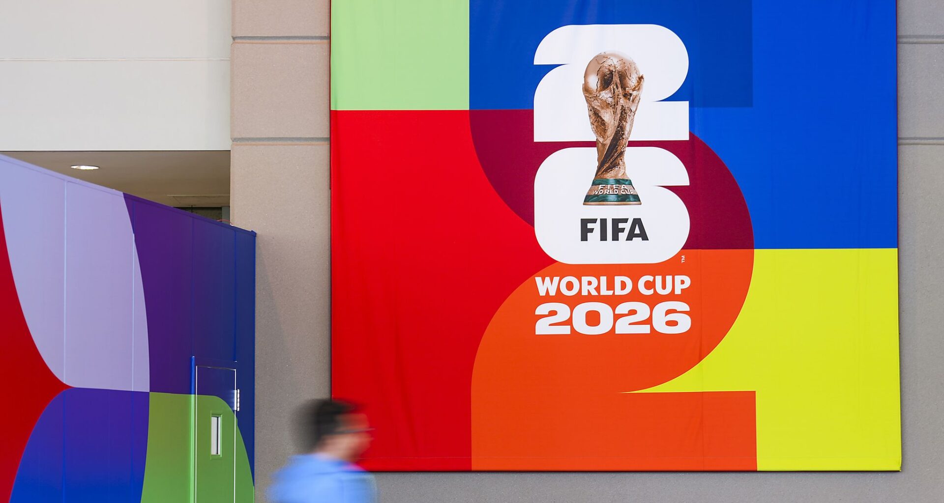 A person passes a banner before opening ceremonies for the  FIFA World Cup 2026 International Broadcast Center (IBC) at the Kay Bailey Hutchison Convention Center, Monday, June 1, 2026, in Dallas.