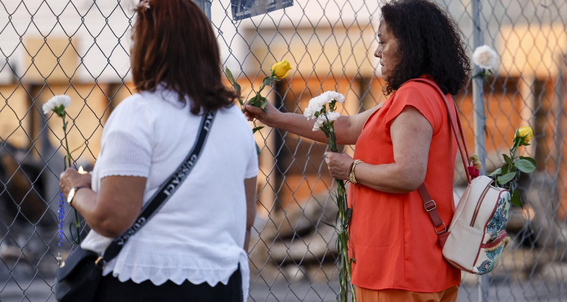 A woman places a flower in a fence at the site of a deadly explosion and fire at The Clyde apartment building in Oak Cliff on Wednesday, June 3, 2026, in Dallas.