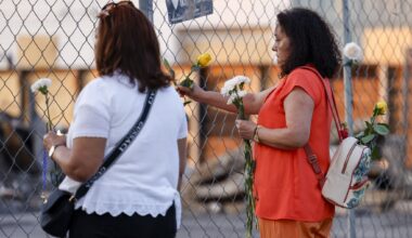 A woman places a flower in a fence at the site of a deadly explosion and fire at The Clyde apartment building in Oak Cliff on Wednesday, June 3, 2026, in Dallas.