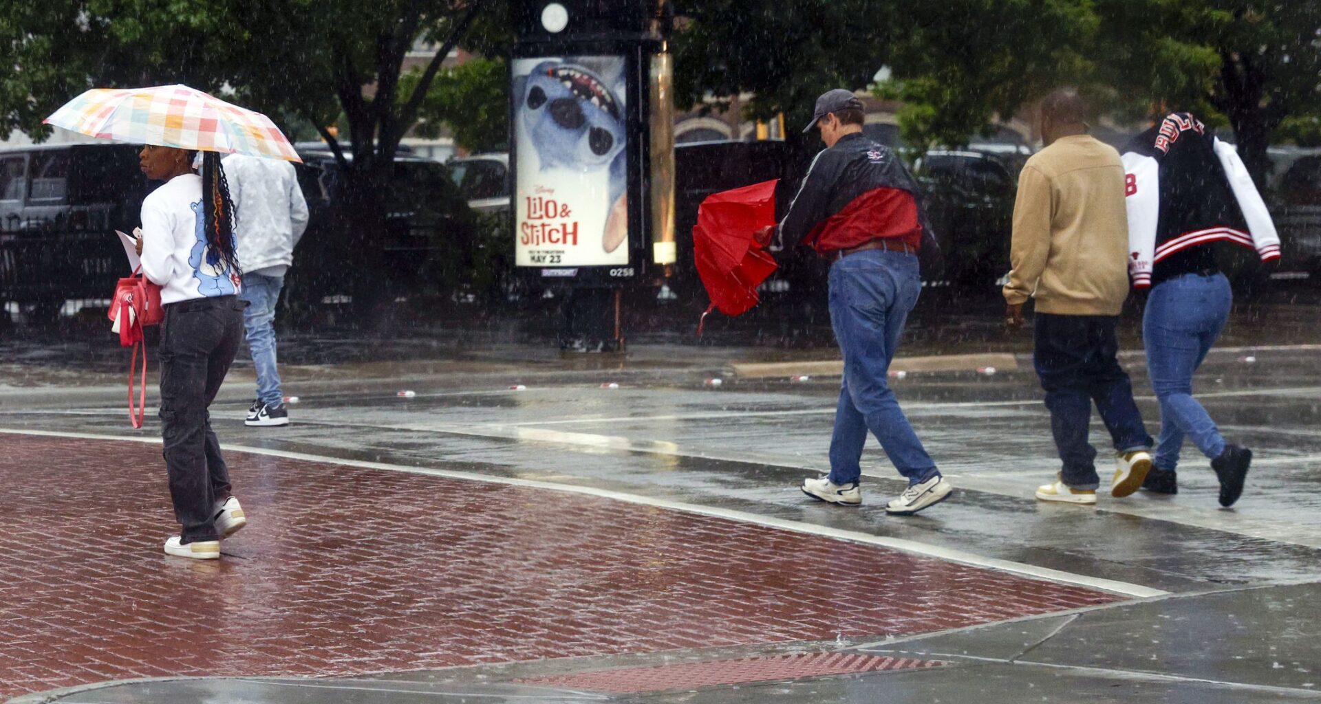 Pedestrians cross Market Street at Commerce Street as rain falls in downtown Dallas, Tuesday, May 6, 2025.