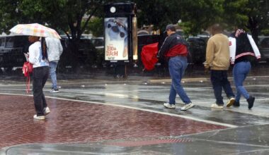 Pedestrians cross Market Street at Commerce Street as rain falls in downtown Dallas, Tuesday, May 6, 2025.