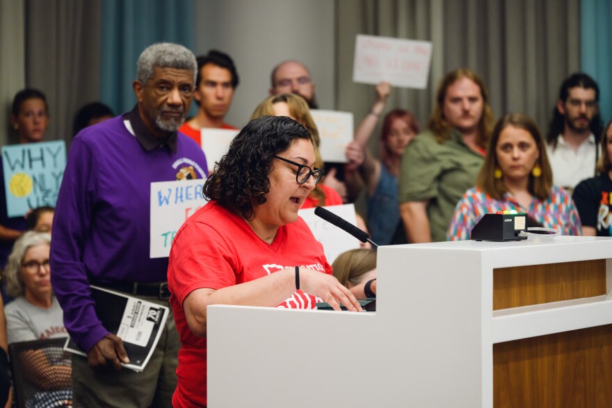A woman stands at a podium speaking.