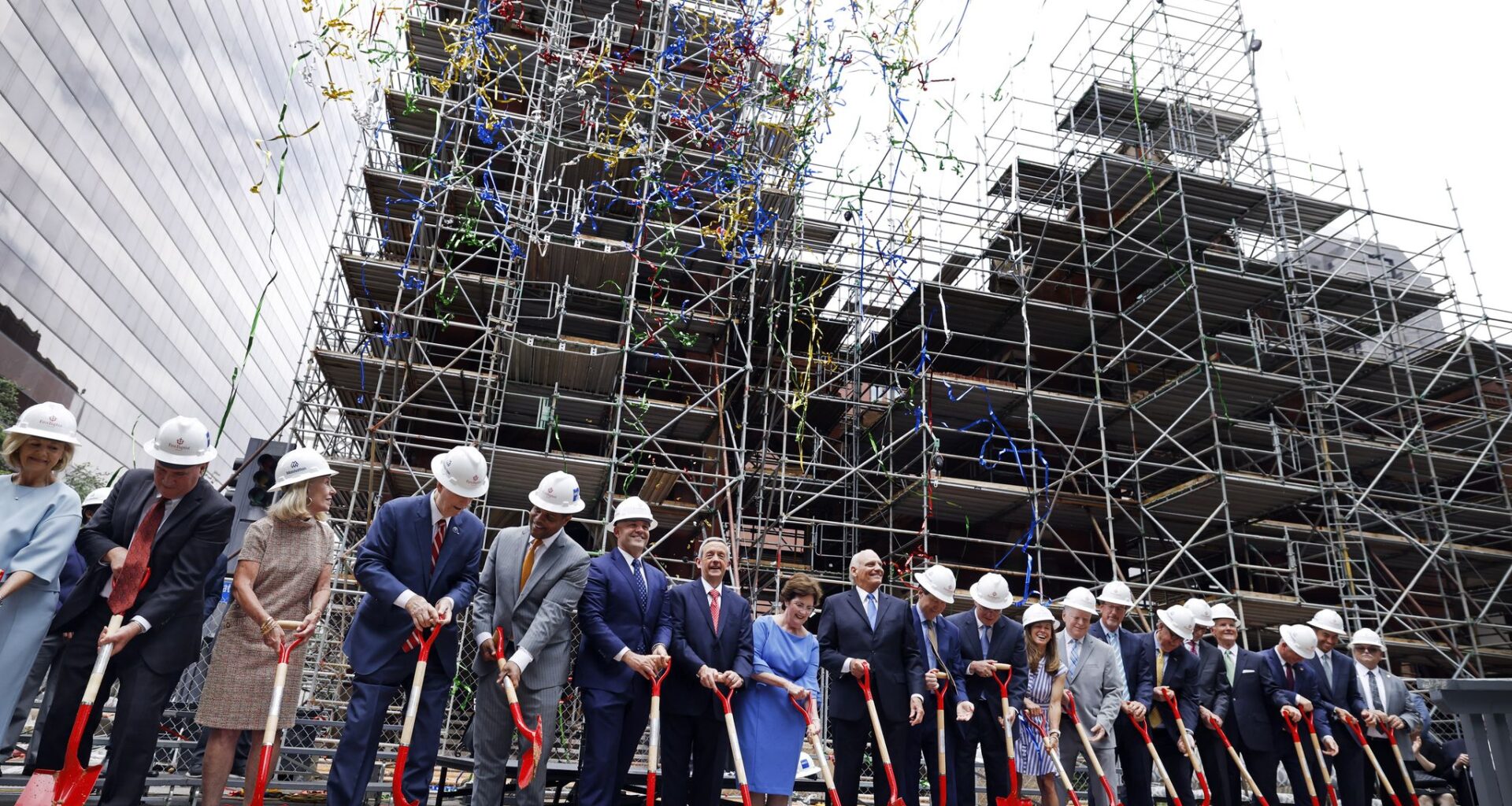 Colorful streamers fall as church and civic officials, including senior pastor Dr. Robert Jeffress and his wife Amy  (center) shovel sand during the First Baptist Church Dallas groundbreaking ceremony for its historic sanctuary in downtown Dallas, June 7, 2026. Scaffolding surrounds what was left of the sanctuary after the devastating fire in 2024.