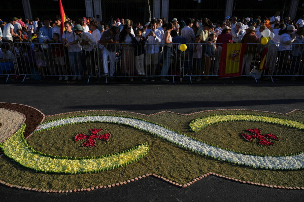 People wait for Pope Leo XIV to preside over Mass marking the Catholic feast of Corpus Christi in Plaza de Cibeles in Madrid, Sunday, June 7, 2026, on the second day of a seven-day apostolic journey to mainland Spain and the Canary Islands. (AP Photo/Alessandra Tarantino)