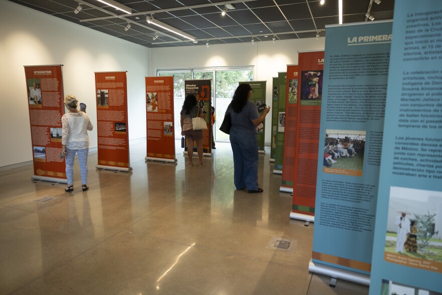 People walk inside a room with vertical banners full of information displayed.