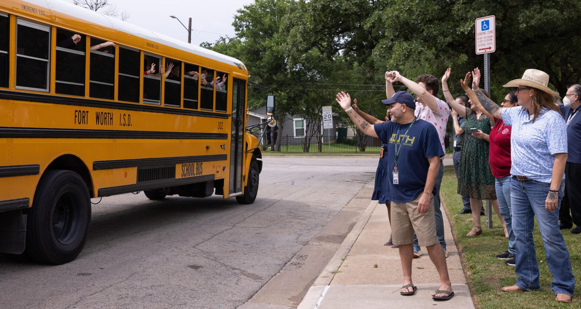 School staff wave to a bus as students leave following the last day of school at International Newcomer Academy, a specialized campus for immigrant and refugee students in Fort Worth, on Thursday, May 21, 2026. 