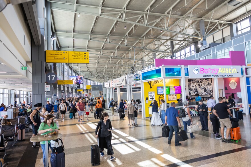 Flyers and employees walk past shops, restaurants, and airplane gates at Austin-Bergstrom International Airport on Monday, April 21, 2025.