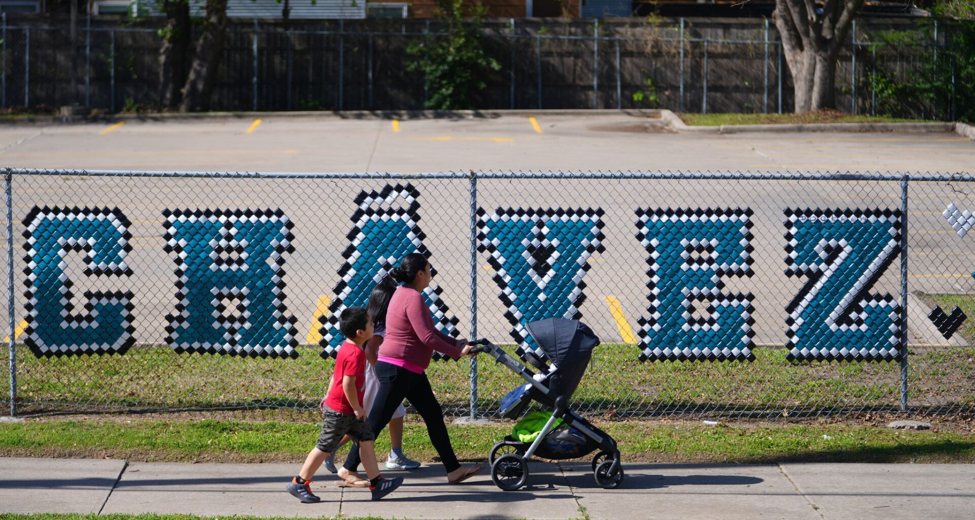Pedestrians walk past the parking lot of the Cesar Chavez Learning Center in Dallas, Thursday, March 19, 2026. (AP Photo/Julio Cortez)