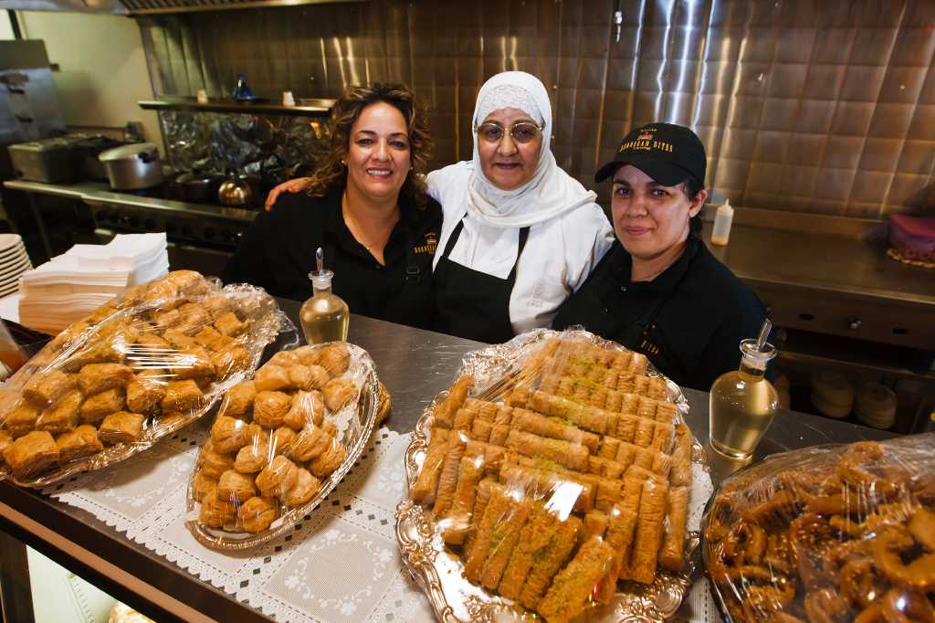 Nadia Elmaroudi (from left), Haja Latifa Elmaroudi and Wafa Elmaroudi behind a counter filled with desserts at Moroccan Bites Tagine.