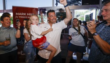 Frisco mayoral candidate Mark Hill pumps his fist as he holds his daughter Emily, 7, as he greets supporters with his wife Tiffany Hill (back right) during a runoff election night watch party at The Frisco Bar &amp; Grill on Saturday, June 13, 2026, in Frisco.