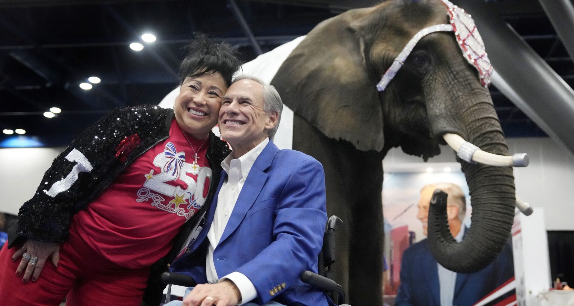 Aida Scott takes a photo with Gov. Greg Abbott on Friday in front of an elephant named Paige at the Texas GOP convention in the George R. Brown Convention Center in Houston.