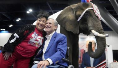 Aida Scott takes a photo with Gov. Greg Abbott on Friday in front of an elephant named Paige at the Texas GOP convention in the George R. Brown Convention Center in Houston.