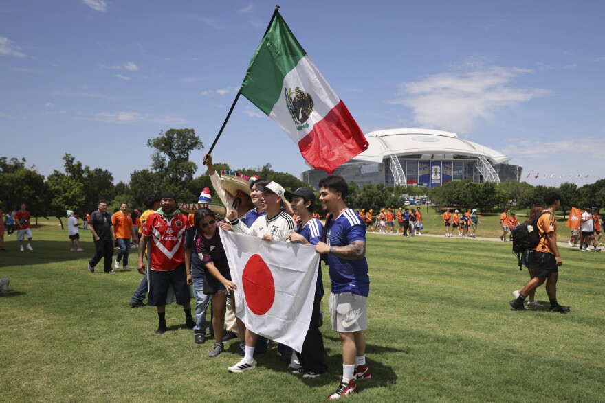 Japanese and Mexican fans hold up a flag with AT&T Stadium, known as Dallas Stadium for the World Cup, in the background before the Netherlands and Japan World Cup game Sunday, June 14, 2026, in Arlington.