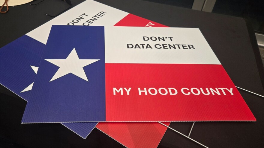 Protest signs reading "Don't Data Center My Hood County" are displayed at a town hall meeting on Wednesday night.