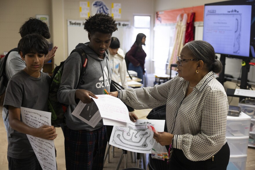 A teacher taking work from three students