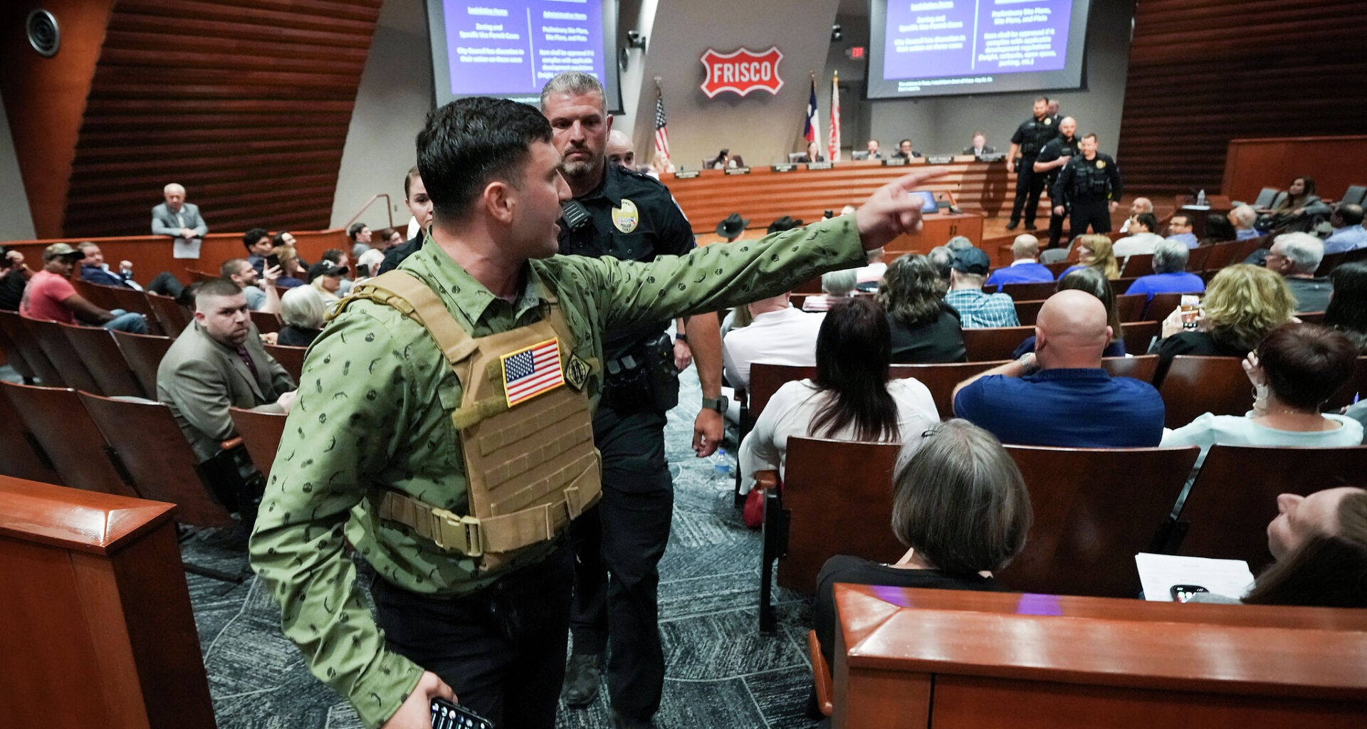 Jake Lang is removed by police for violating decorum rules while speaking in opposition to the proposed construction of a mosque and two temples during a city council meeting in Frisco, Tuesday, May 19, 2026.