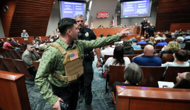 Jake Lang is removed by police for violating decorum rules while speaking in opposition to the proposed construction of a mosque and two temples during a city council meeting in Frisco, Tuesday, May 19, 2026.