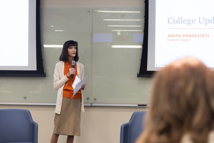 Anita Vangelisti holding a microphone in front of a white board in a classroom.