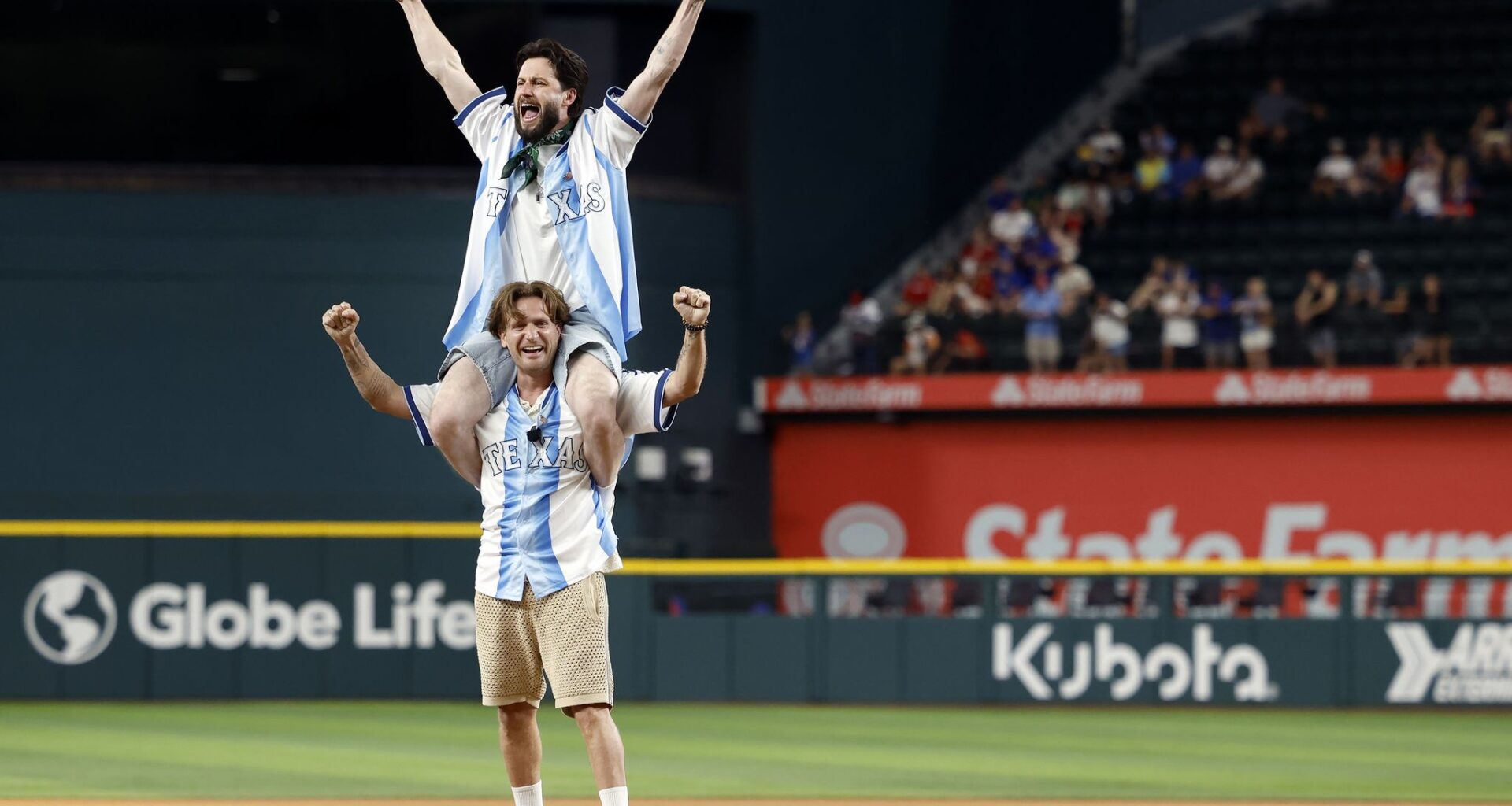 Highly popular British internet duo Woody & Kleiny react after throwing out the ceremonial first pitch before the Texas Rangers game against the Minnesota Twins at Globe Life Field in Arlington, June 16, 2026. Paul Wood (bottom) and Paul Klein are continuously streaming their lives to millions around the globe.