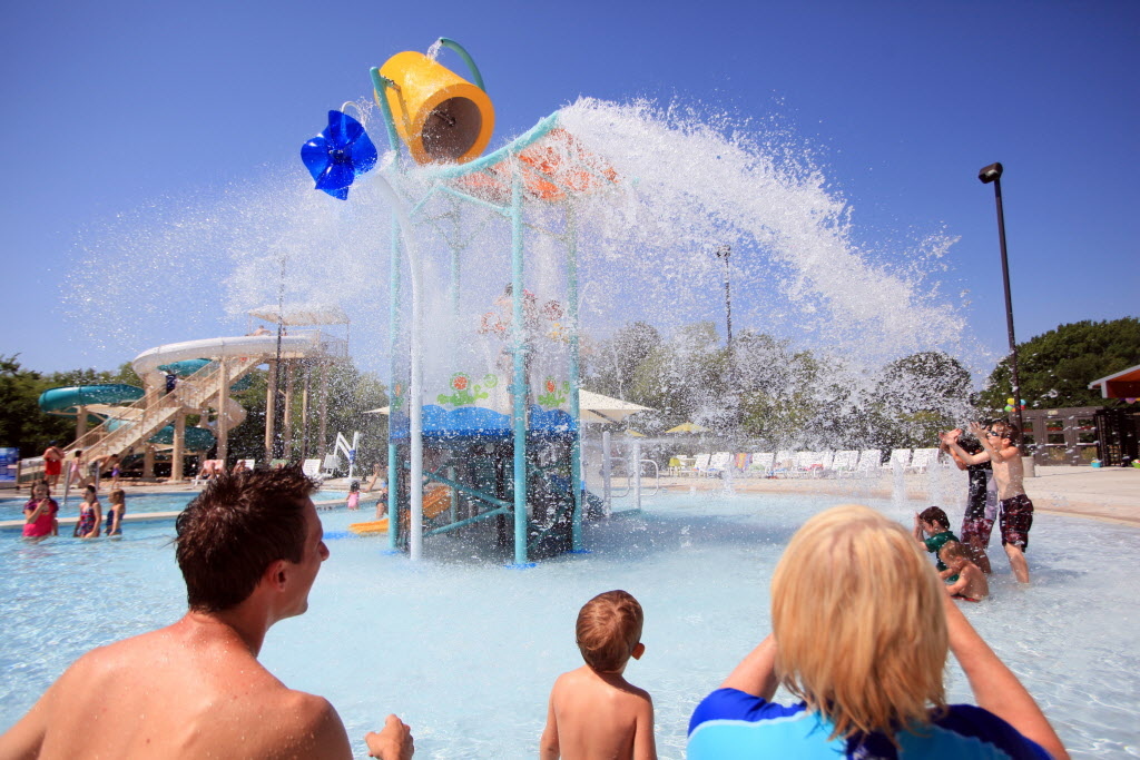 Brian Buchek, left, and Linda Buchek, right, watch as their family is soaked with an oversize bucket of water at the splash playground, during the grand opening of the Heights Family Aquatic Center, on July 12, 2013 in Richardson. The $4.4 million amenity complements the $11 million renovation of Heights Recreation Center, which was completed in May.