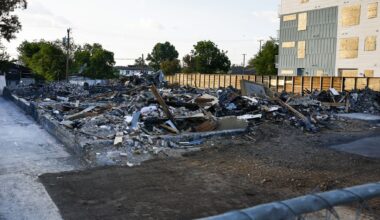 Debris from a deadly explosion and fire at The Clyde apartment building is seen behind a fence in Oak Cliff on Wednesday, June 3, 2026, in Dallas. Three people were killed in the May 28 explosion and fire at the apartment building.