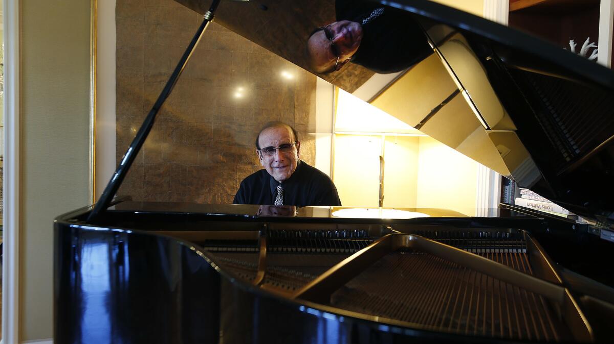 Clive Davis sits behind a piano. 