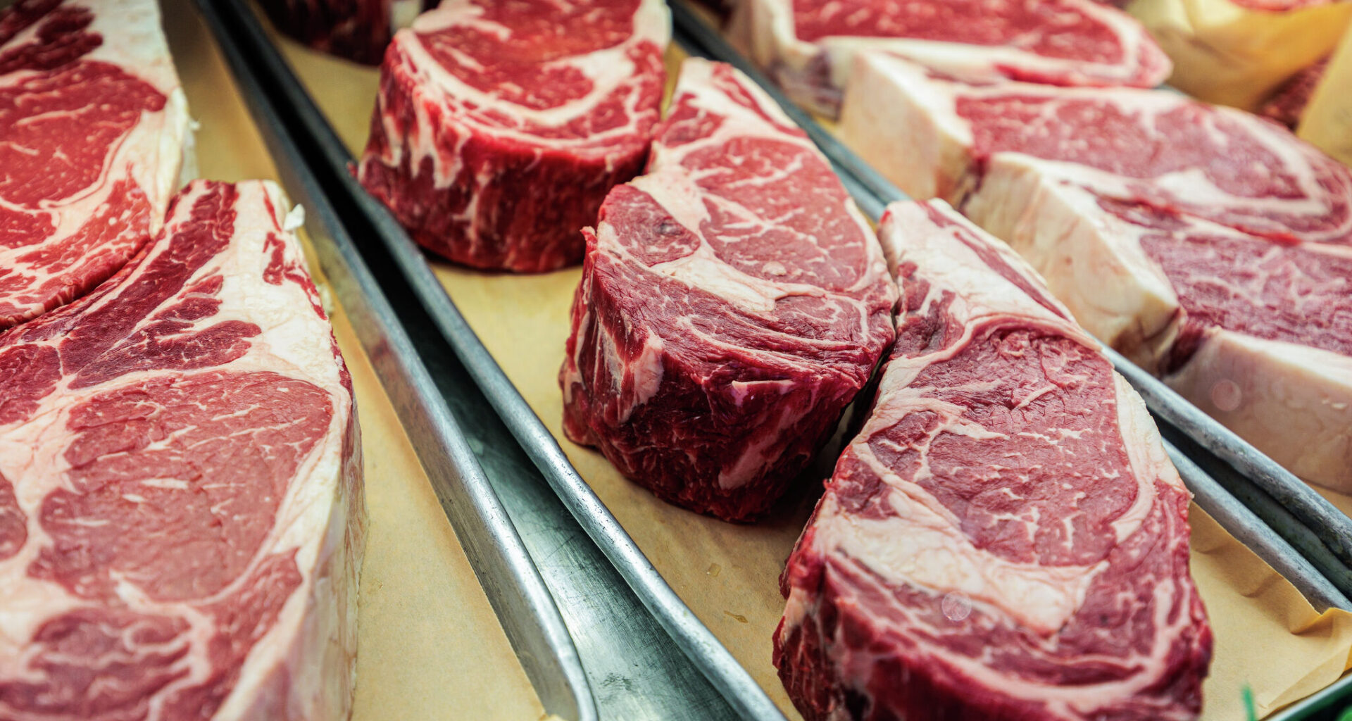 Close-up of large cuts of steak at a butcher shop.